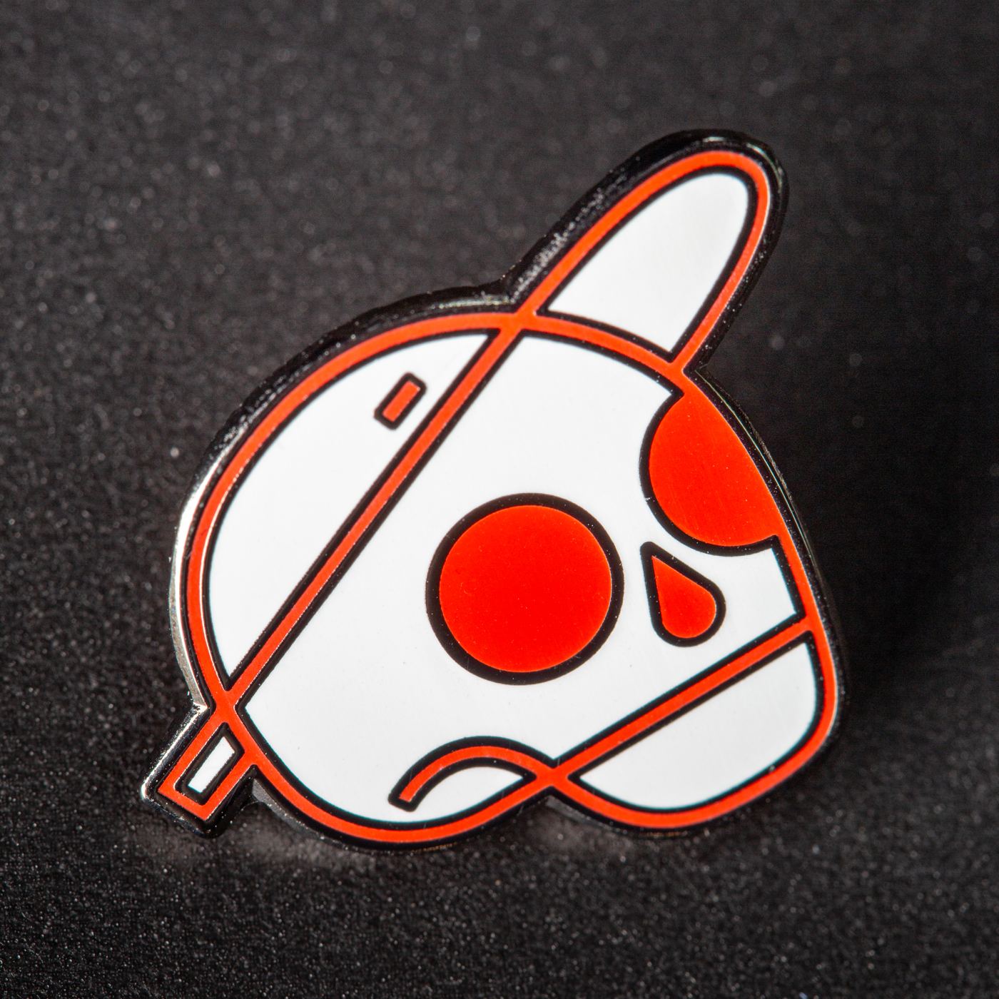 Macro of an enamel pin on black textured fabric